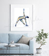 Framed watercolor painting of a woman doing a triangle yoga pose with her muscular system showing beneath her skin. The painting is hanging over a blue couch.