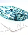 Unframed watercolor painting at an angle showing a teal and blue transverse cut of the brain.