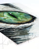 Unframed watercolor painting of a zoomed in perspective of a green cat's eye. The hair surrounding the eye is black and white. The painting is at an angle.