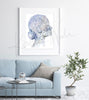 Framed watercolor painting of a head and neck showing the lymphatic system. The painting is hanging over a blue couch.