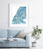 Framed watercolor painting of an abstract body with labeled muscles. The painting is hanging over a blue couch.