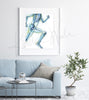 Framed watercolor painting of a runner, showing the skeletal structure beneath. The painting is hanging over a blue couch.