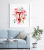 Framed watercolor painting of a uterus with flowers around. The painting is hanging over a blue couch.